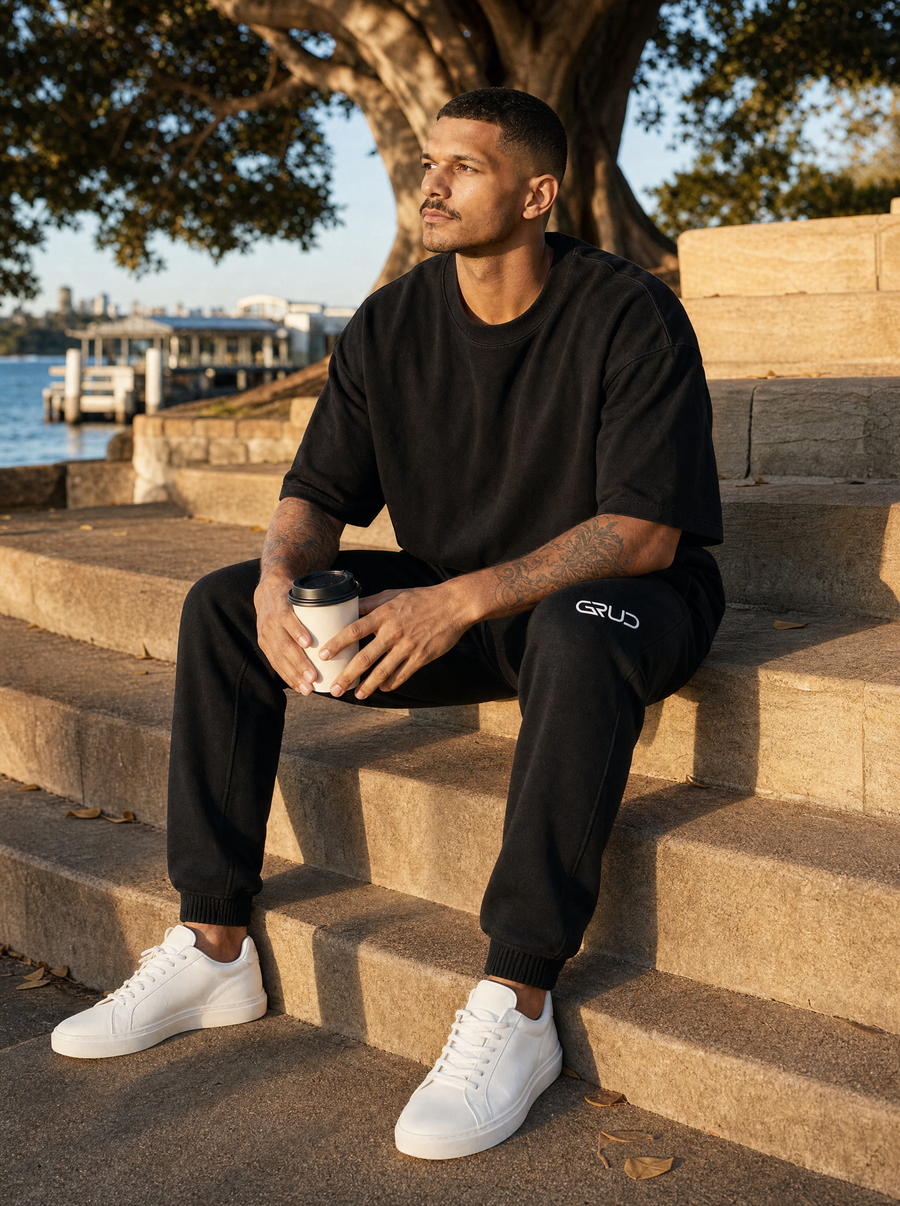 Man in the GRUD tee and sweat pants sitting on sandstone steps by Sydney Harbour